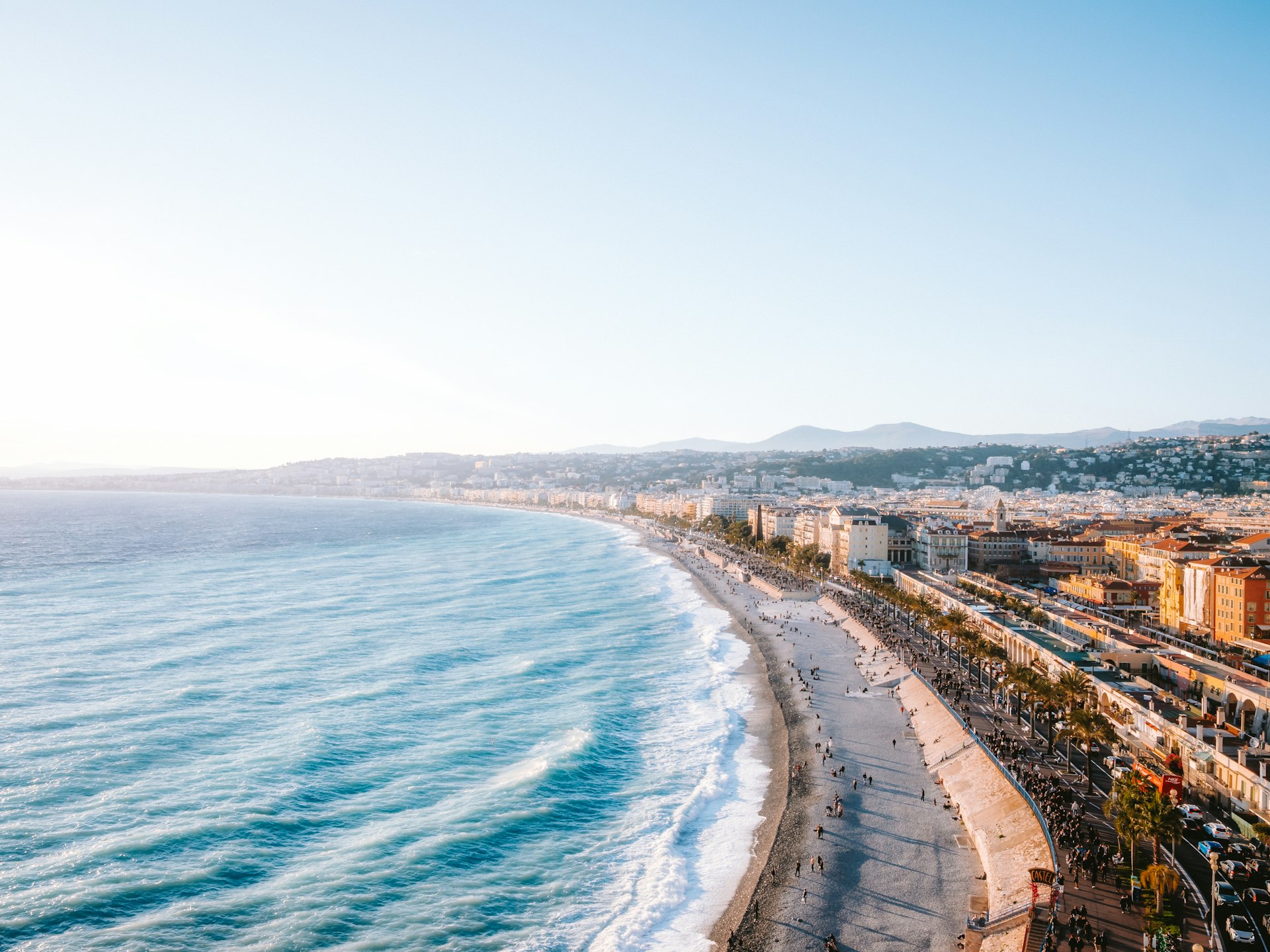 Coastal city skyline with ocean waves and clear sky.